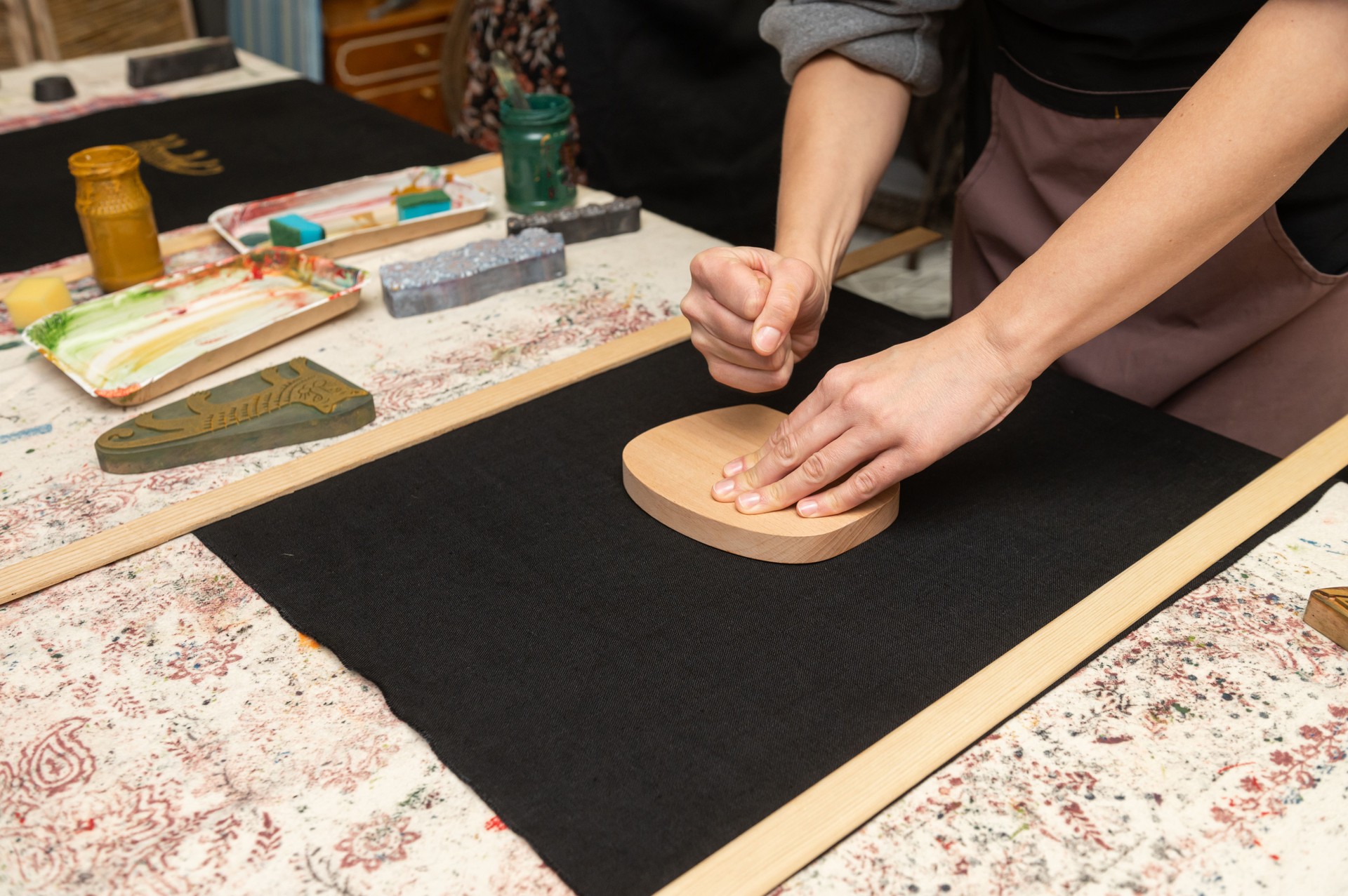 Female artisan printing on fabric with wooden block in craft studio